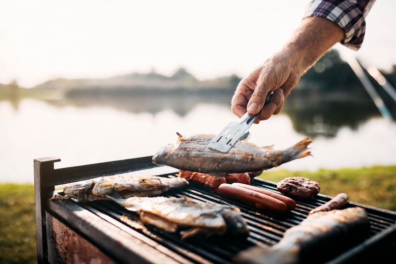 Close-up of senior man preparing the fish he caught while camping in nature.